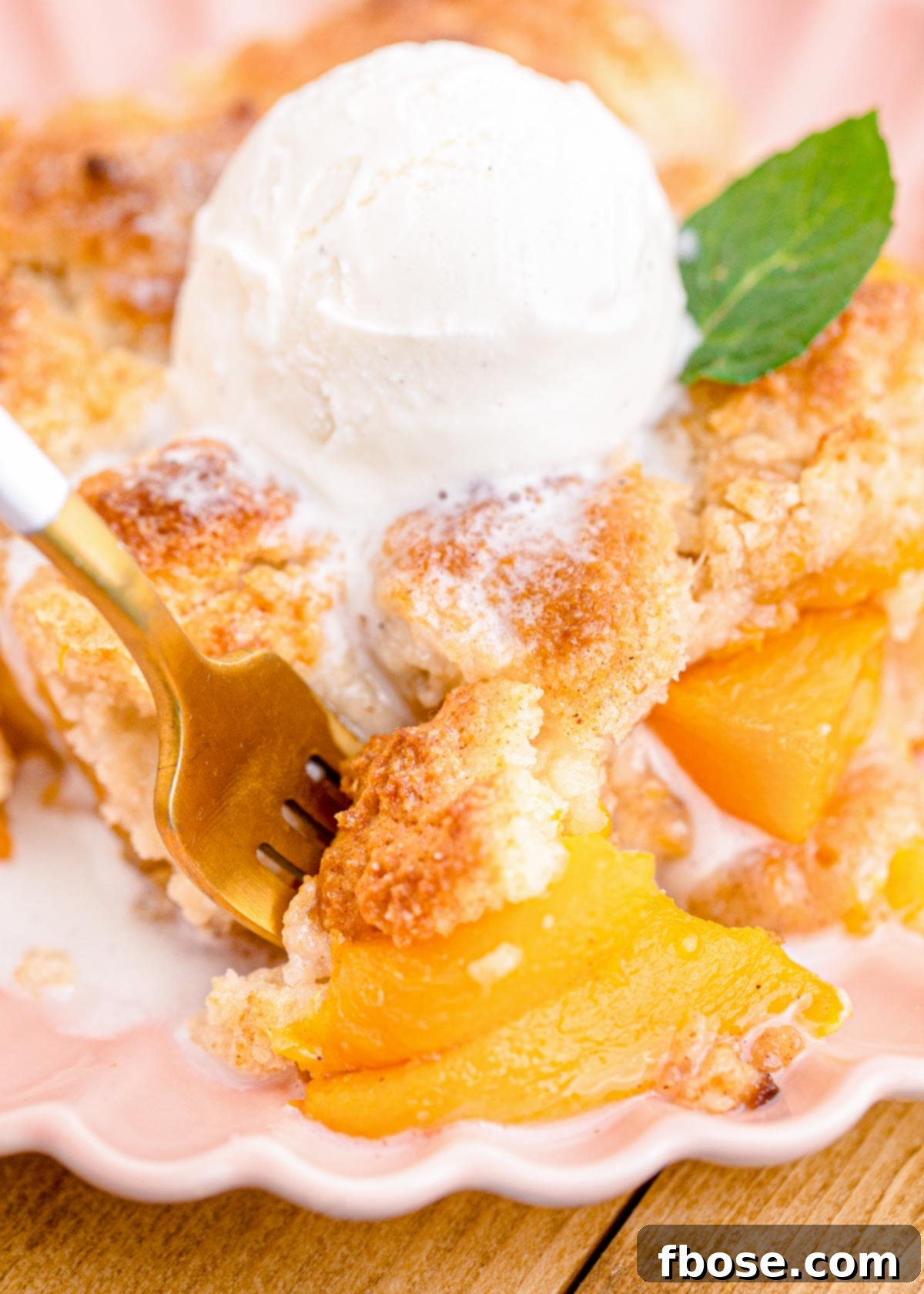 A fork taking a bite out of a slice of peach cobbler.