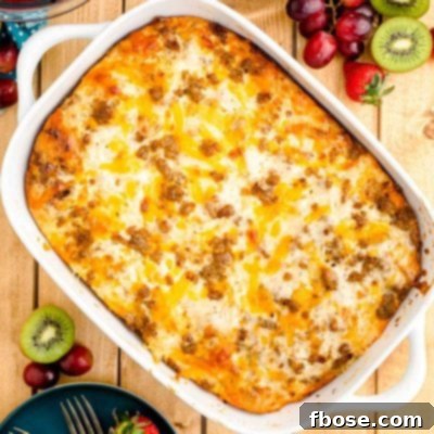 Overhead photo of a biscuits and gravy casserole on a wooden table with fruits and serving plates around it.