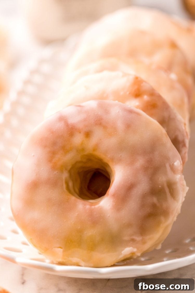 Glazed donuts on a white serving platter.