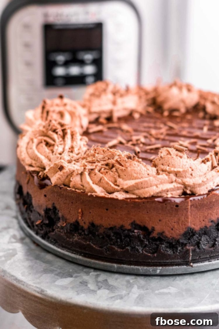 Decadent Instant Pot Chocolate Cheesecake 4 Close up photo of a chocolate instant pot cheesecake on a metal cake stand with an instant pot in the background.