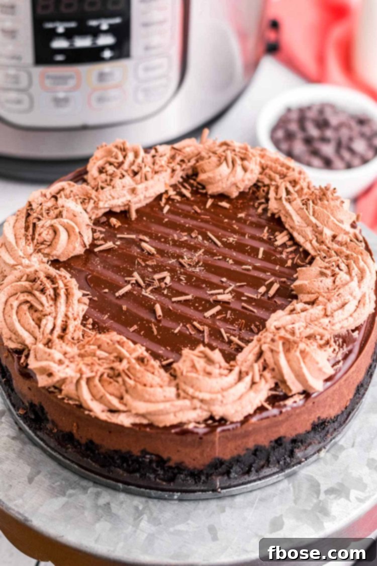 Decadent Instant Pot Chocolate Cheesecake 7 Instant pot chocolate cheesecake on a metal cake stand with an instant pot in the background.