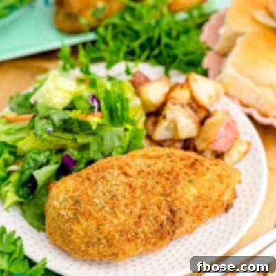 Close up photo of shake and bake chicken on a white plate with a garden salad and roasted potatoes.