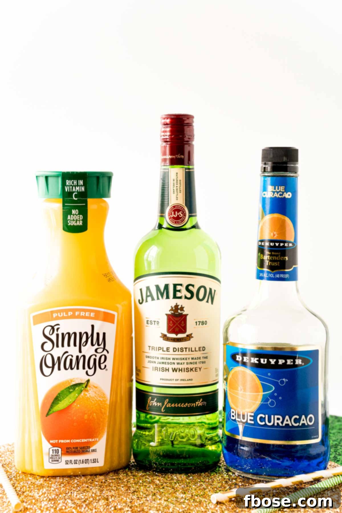 Jig Juice 4 A bottle of orange juice, Jameson, and Blue Curacao on a gold placemat.