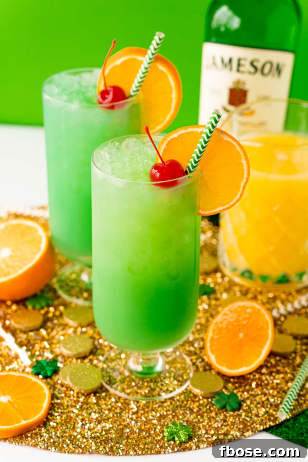 Jig Juice 8 Two glasses filled with a green cocktail on a gold placemat.