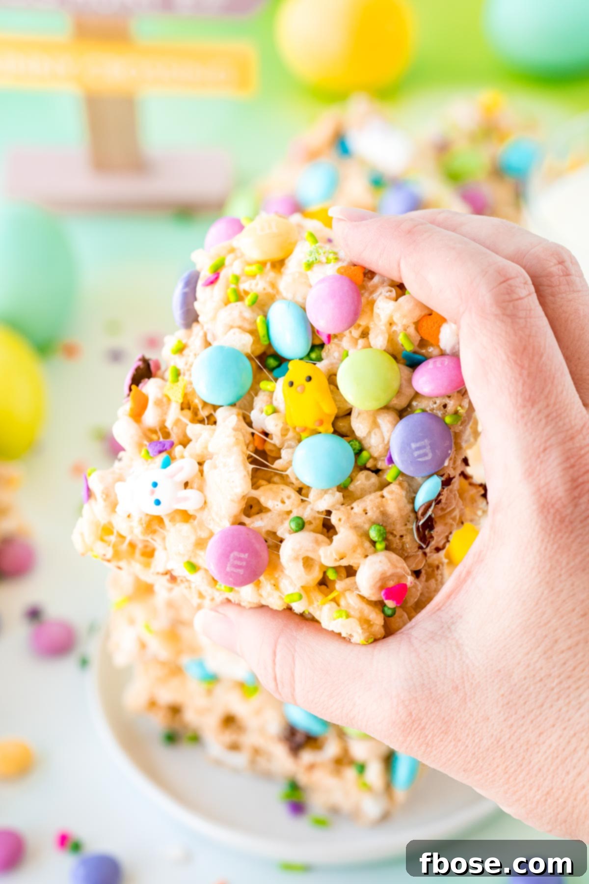 A woman's hand holding a Easter rice krispie treat to the camera.