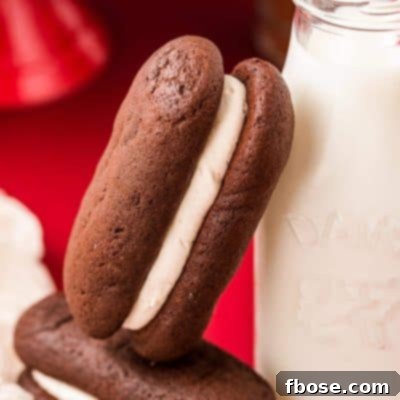 Homemade devil dogs on a red surface, on leaning against a glass milk bottle.