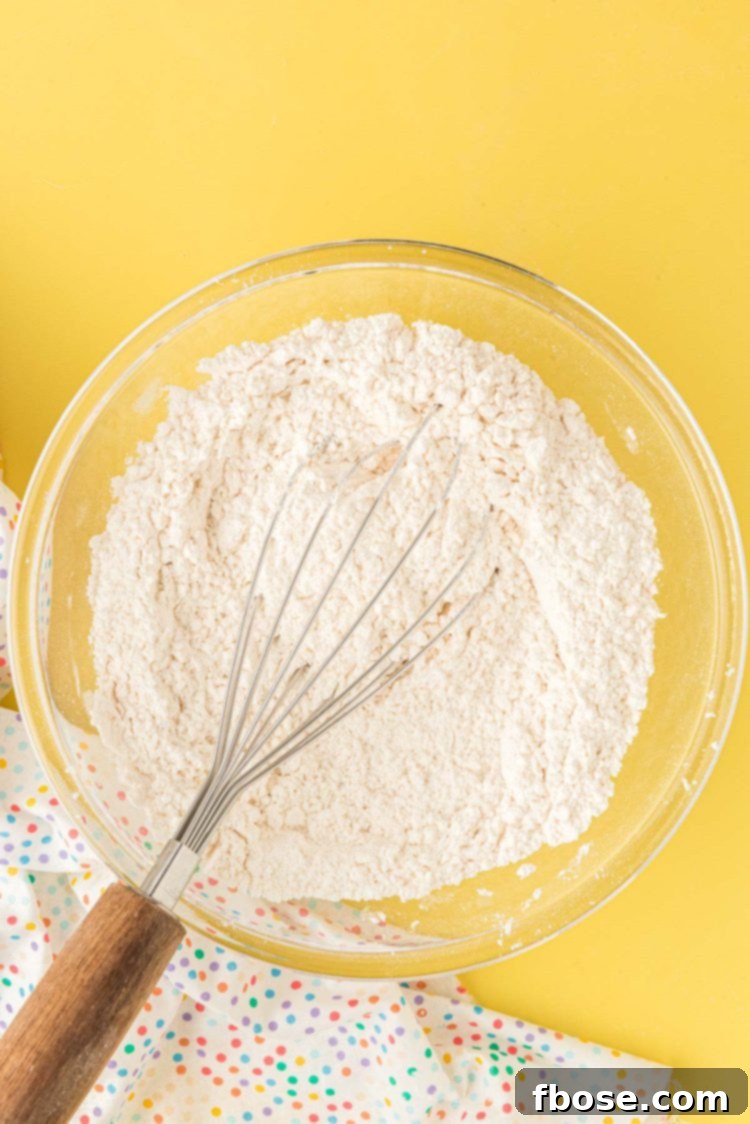 All-purpose flour and cornstarch beautifully whisked together in a clear glass mixing bowl, showing a uniform blend.