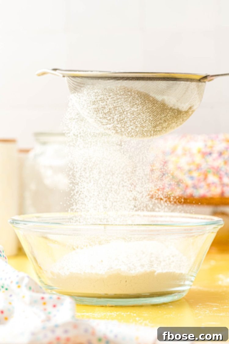 All-purpose flour and cornstarch mixture being sifted through a fine-mesh sieve, ensuring a light and uniform cake flour substitute.
