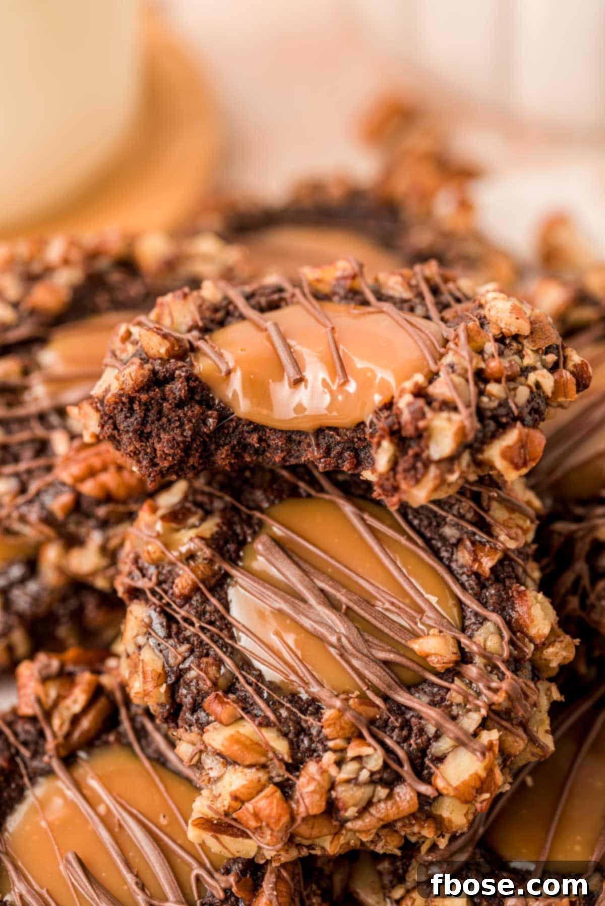 Decadent Turtle Thumbprint Delights 2 Close up of Chocolate Turtle Thumbprint Cookies piled on top of each other.