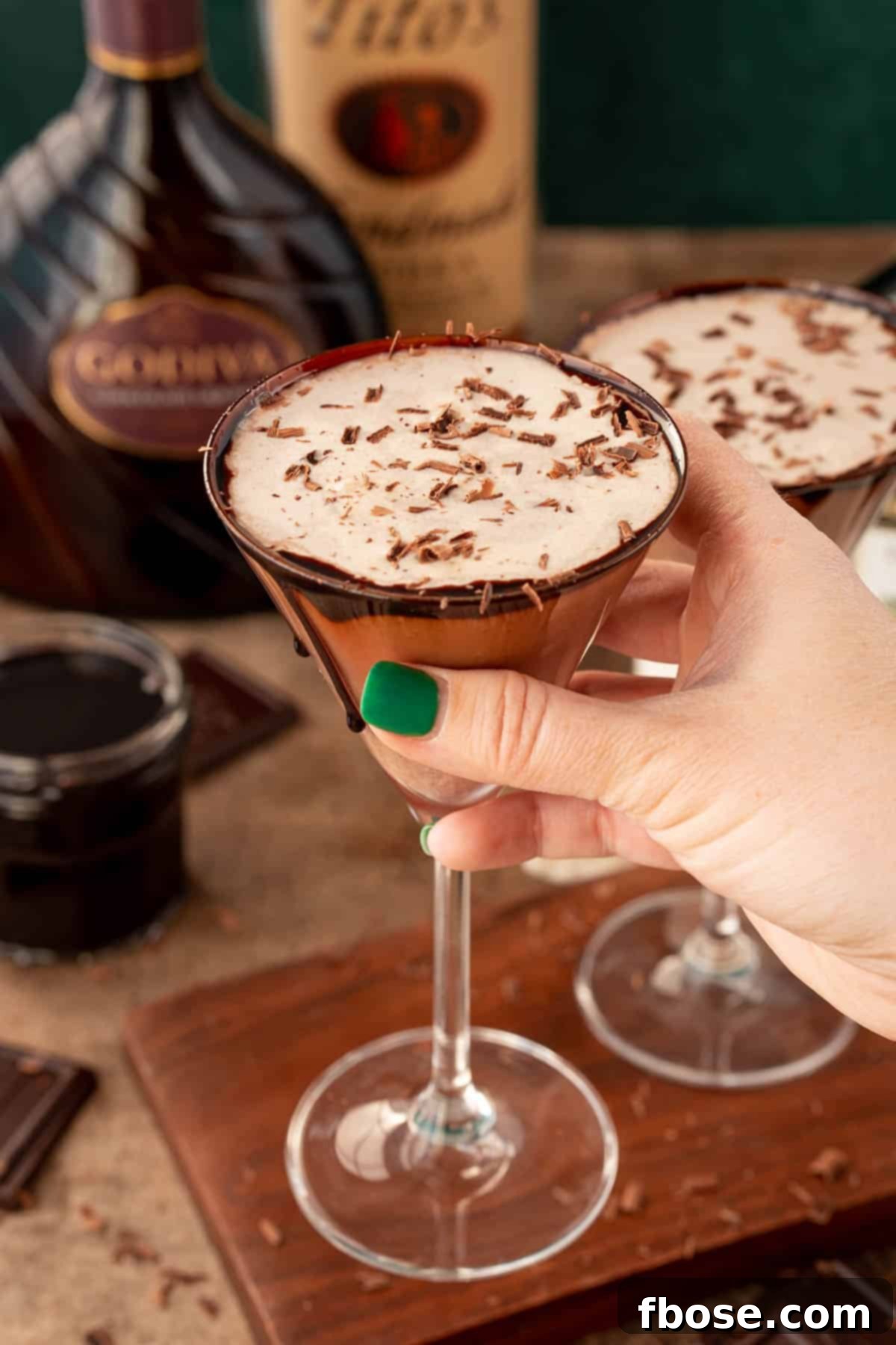 A woman's hand holding a chocolate martini to the camera.