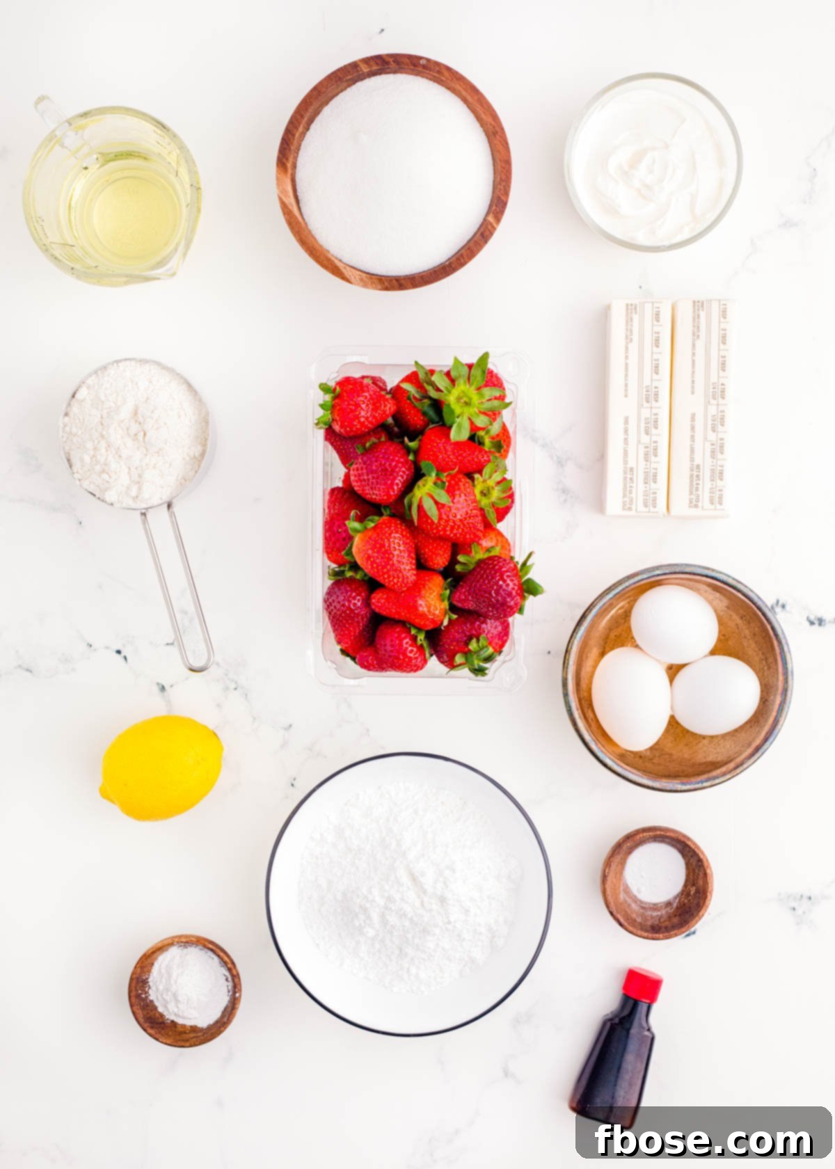 Ingredients to make strawberry sheet cake on a marble surface.