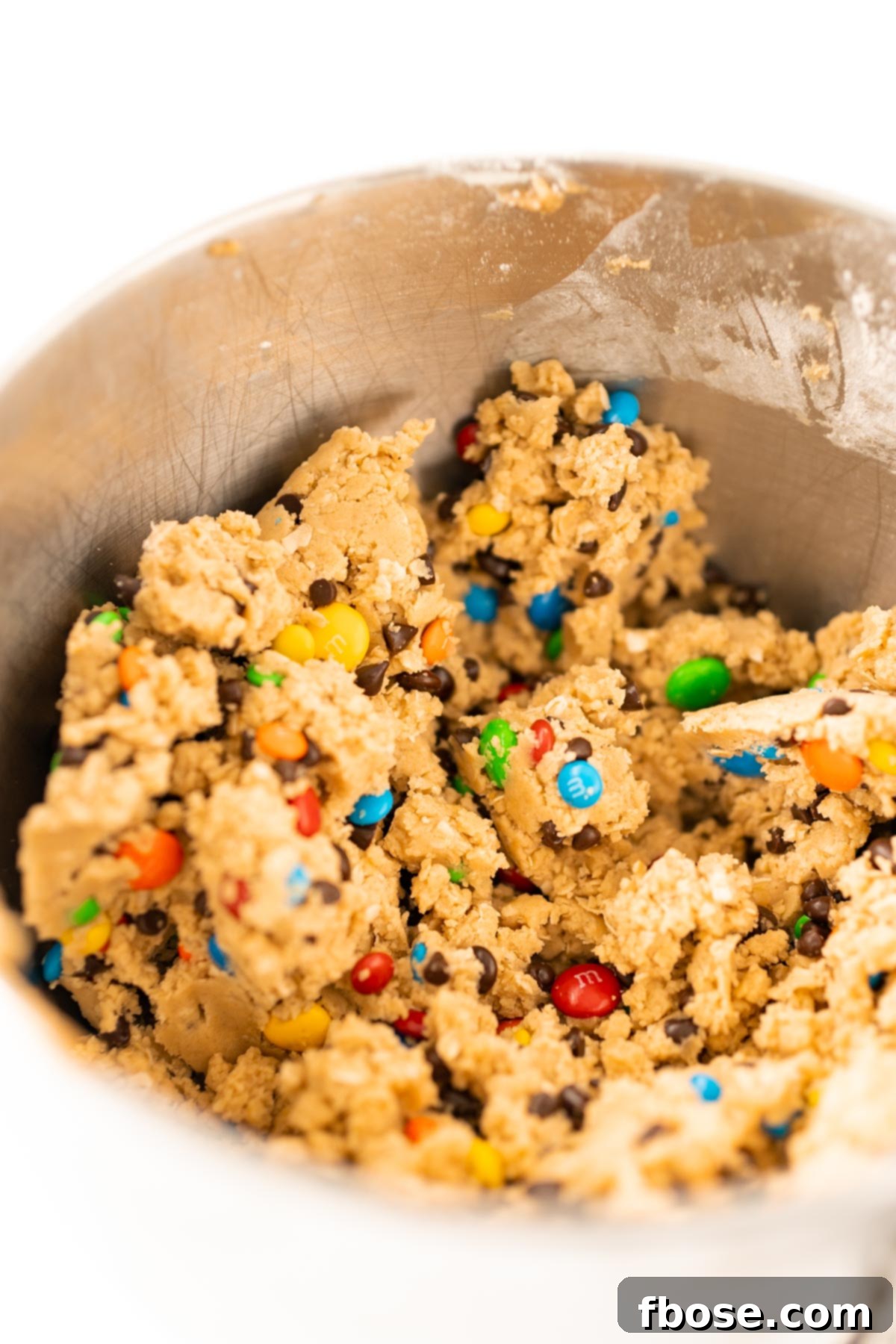 Edible monster cookie dough in a metal mixing bowl.