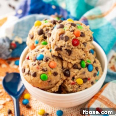 Close up of edible monster cookie dough in a white bowl on a blue and orange napkin.