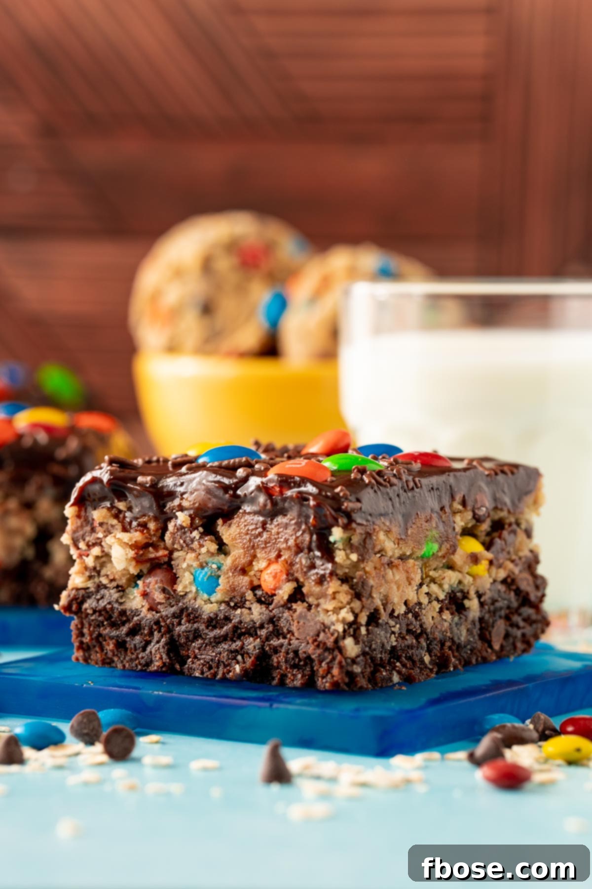 Close up of a slice of monster cookie dough brownies on a blue coaster.