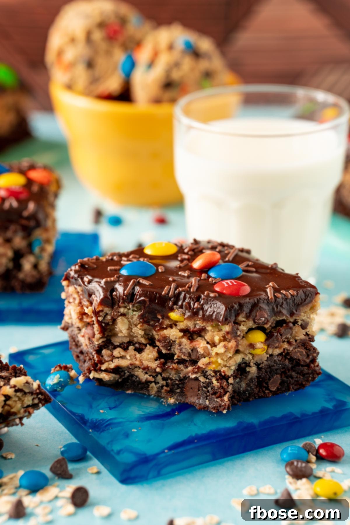 A monster cookie dough brownie on a blue coaster with a bite taken out of it.