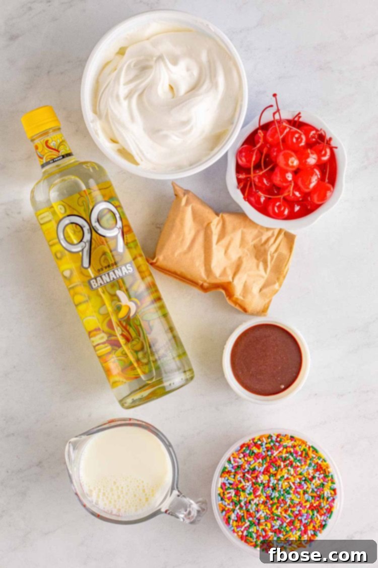 Ingredients to make banana split pudding shots laid out on a gray countertop, including a box of pudding mix, milk, banana liqueur, Cool Whip, and various toppings.
