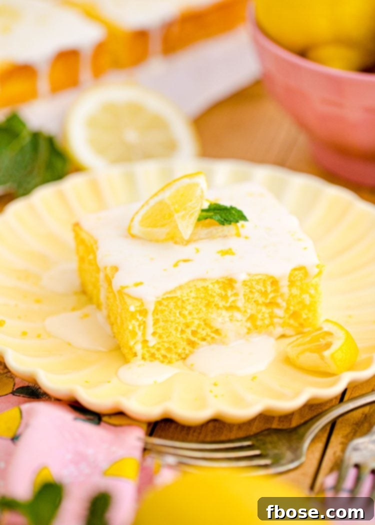 Close-up photo of a generous slice of moist lemon sheet cake on a bright yellow plate, showcasing the fluffy texture and glistening lemon glaze.