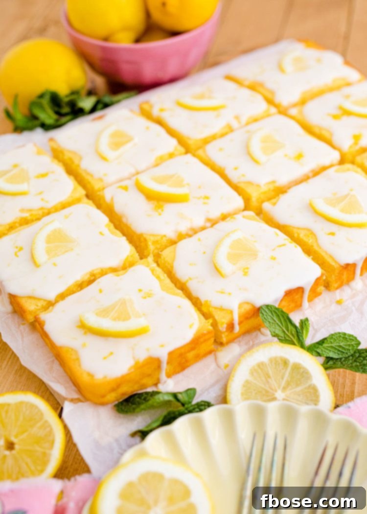 A perfectly cut lemon sheet cake, glistening with glaze, arranged in neat square slices ready for serving, highlighting its inviting appearance.