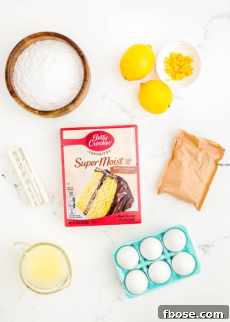 Various ingredients for lemon sheet cake, including a box mix, lemons, eggs, and butter, neatly prepped on a sleek marble surface.