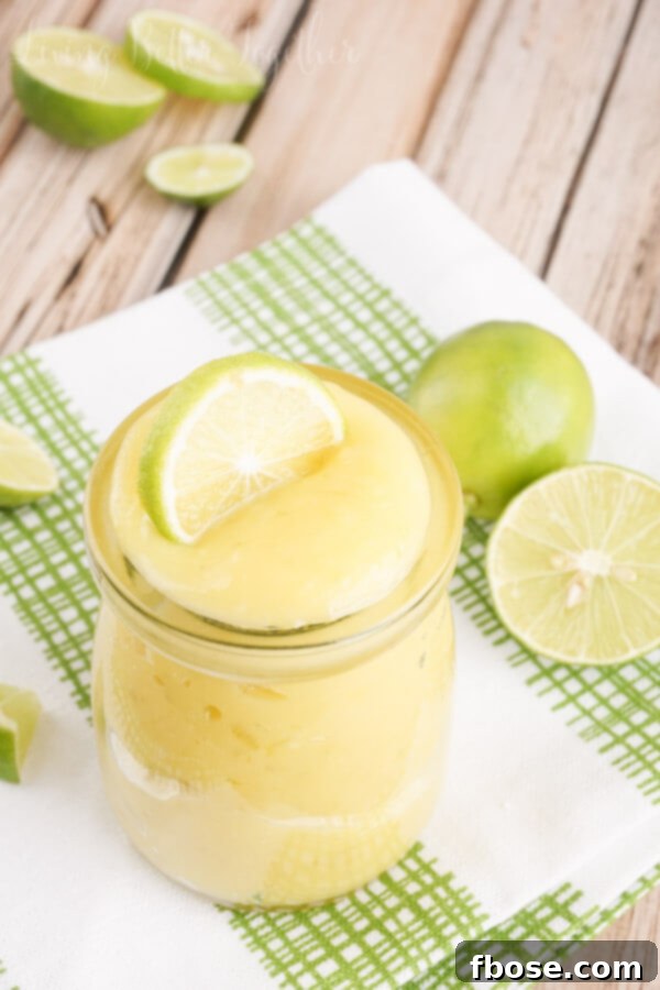 Close-up of freshly made Key Lime Curd in a jar, showcasing its smooth texture and bright color, with a spoon nearby, inviting a taste.