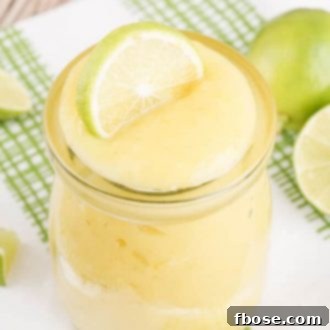 Homemade Key Lime Curd in a decorative bowl, garnished with vibrant fresh key lime slices and a sprig of mint, ready to be served.