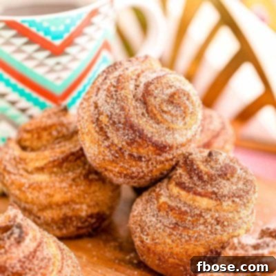 Cruffins stacked on a wooden cutting board with a mug of coffee in the background.