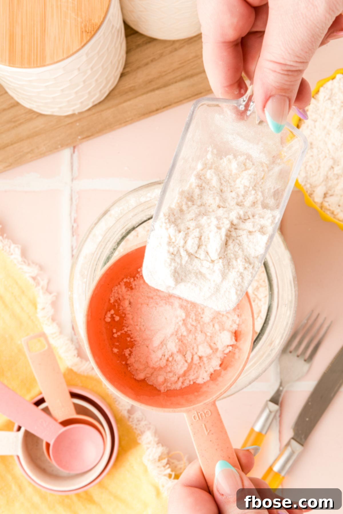 A scoop gently transferring flour into a measuring cup, demonstrating the spoon and level technique.
