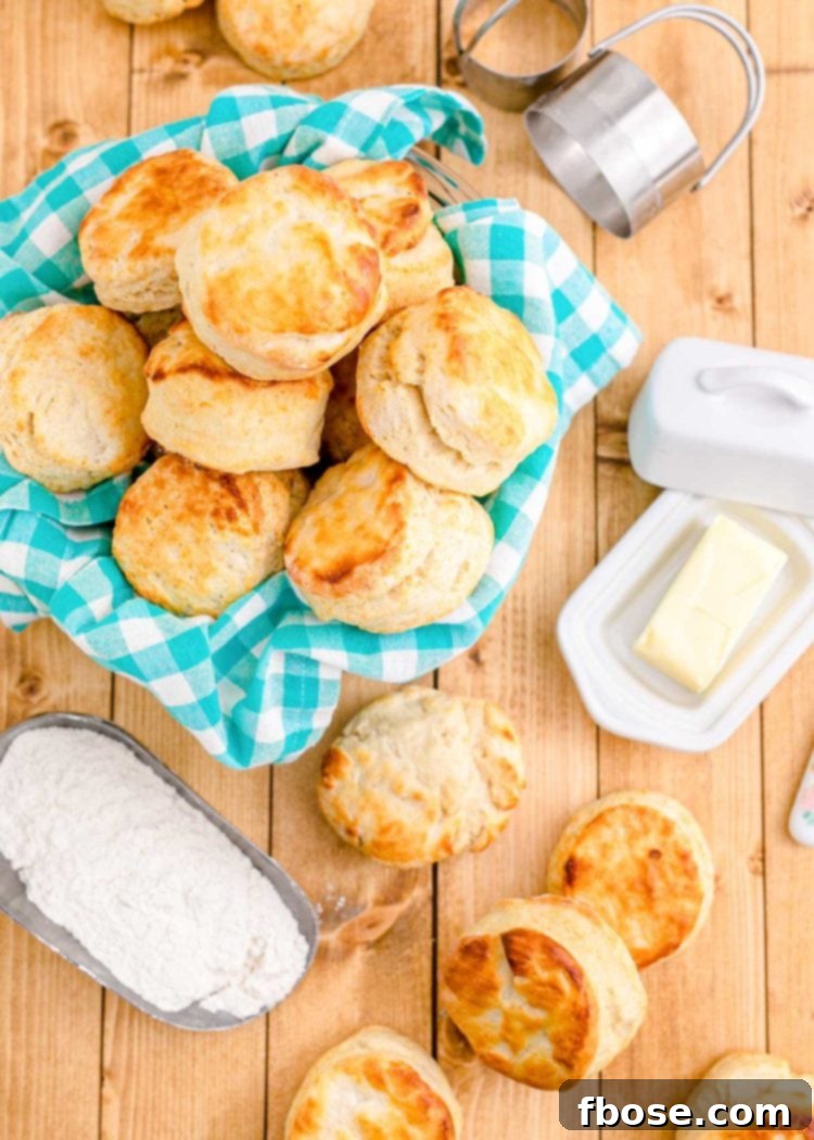 Buttermilk biscuits in a basket with a teal napkin and on a wooden table.