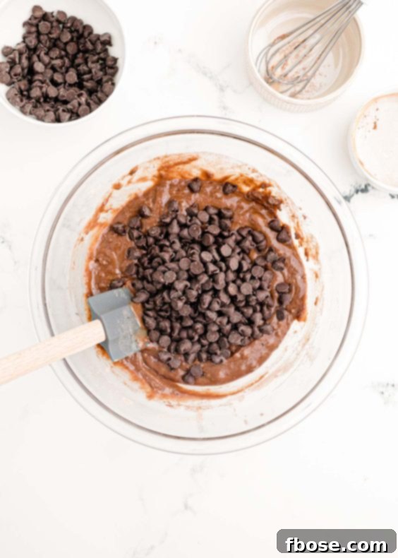 Ultimate Homemade Crockpot Chocolate Cake 11 Chocolate chips being folded into a bowl of chocolate cake batter.