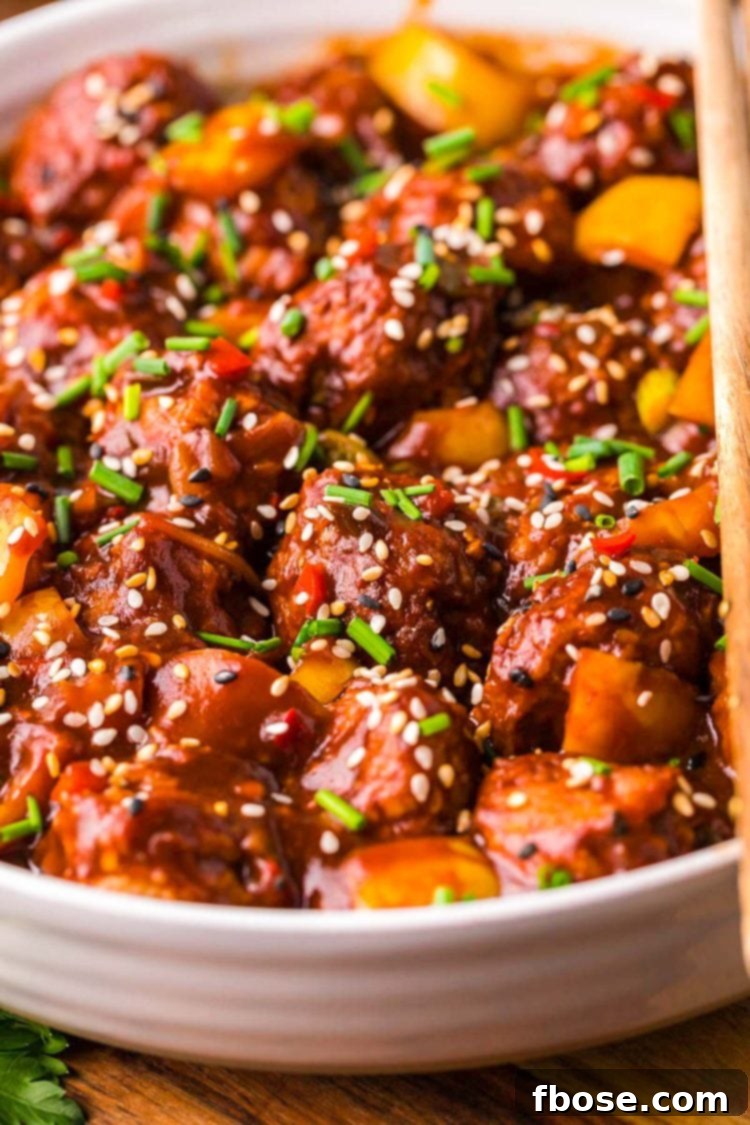 Close up of chicken manchurian in white bowl on a wooden table with chopsticks resting together on top of the bowl.
