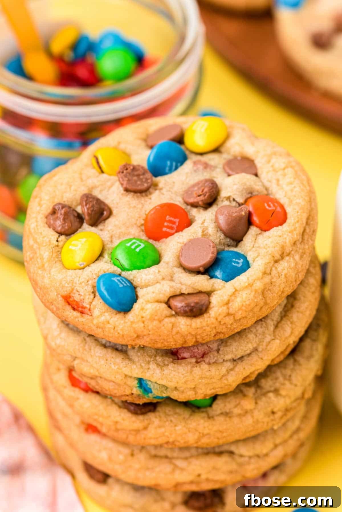 A perfectly arranged stack of M&M cookies, highlighting their uniform size, soft centers, and colorful candy toppings.