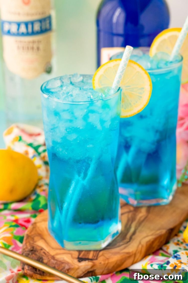 Close-up of a Sex in the Driveway cocktail with a vibrant blue color, lemon slice, and a straw.