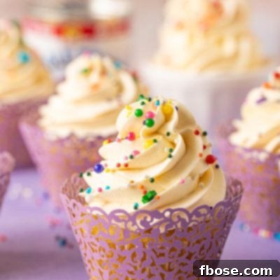A cupcake topped with Russian buttercream on a purple surface.