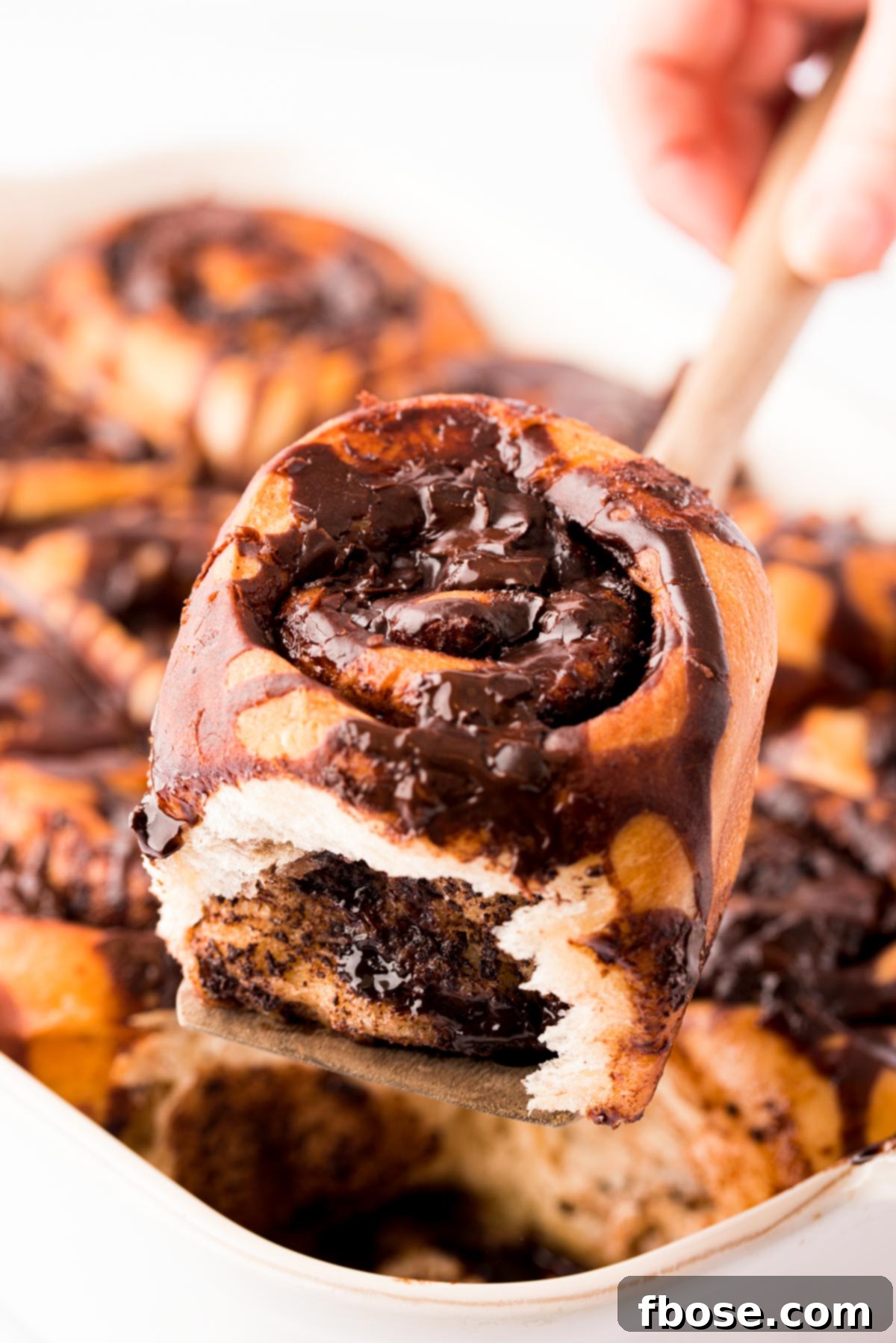 Decadent Chocolate Cinnamon Swirls 2 A spatula lifting a chocolate cinnamon roll out of the pan.