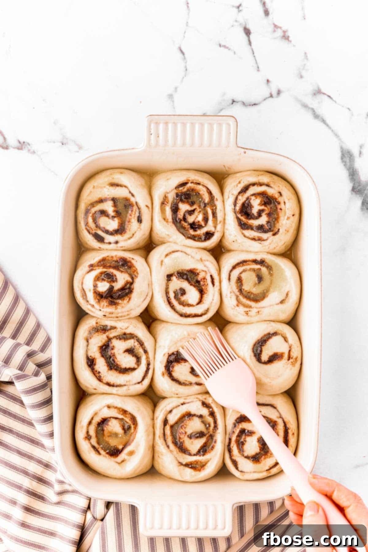 Decadent Chocolate Cinnamon Swirls 14 Raised cinnamon rools being brushed with butter before baking.