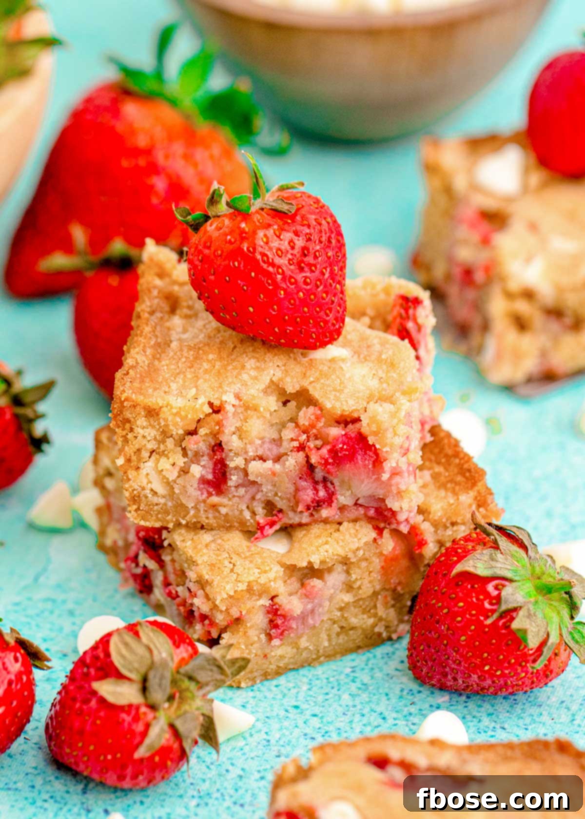 Close up photo of two strawberry blondies stacked on top of each other on a blue surface.