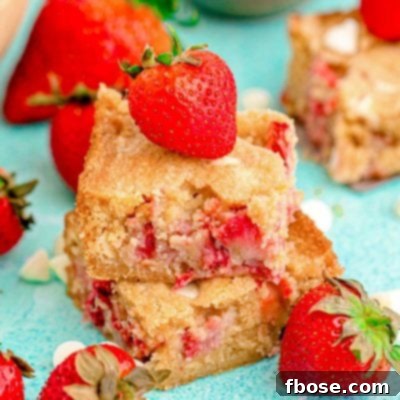 Close up photo of two strawberry blondies stacked on top of each other on a blue surface.