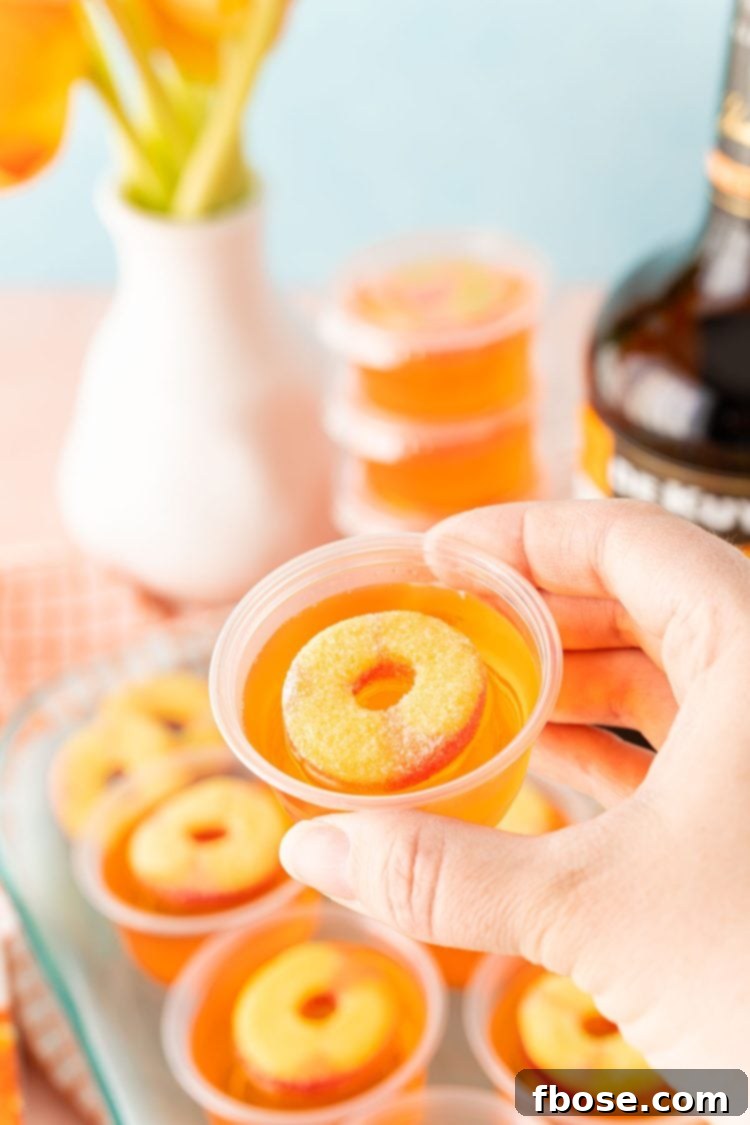 Peachy Keen Jell-O Shots 6 A woman's hand holding a jello shot to the camera.