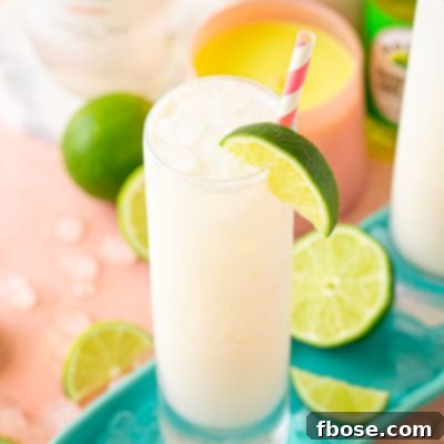 Close up of a RumChata Malibu Lime and Soda cocktail in a tall glass with limes around it.