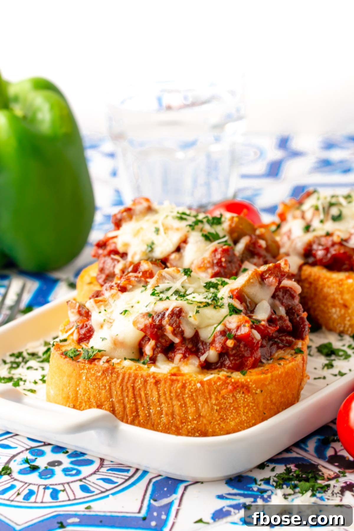 Close up photo of Texas toast sloppy joes on a white plate, showcasing the rich, saucy beef and melted cheese on golden Texas toast.