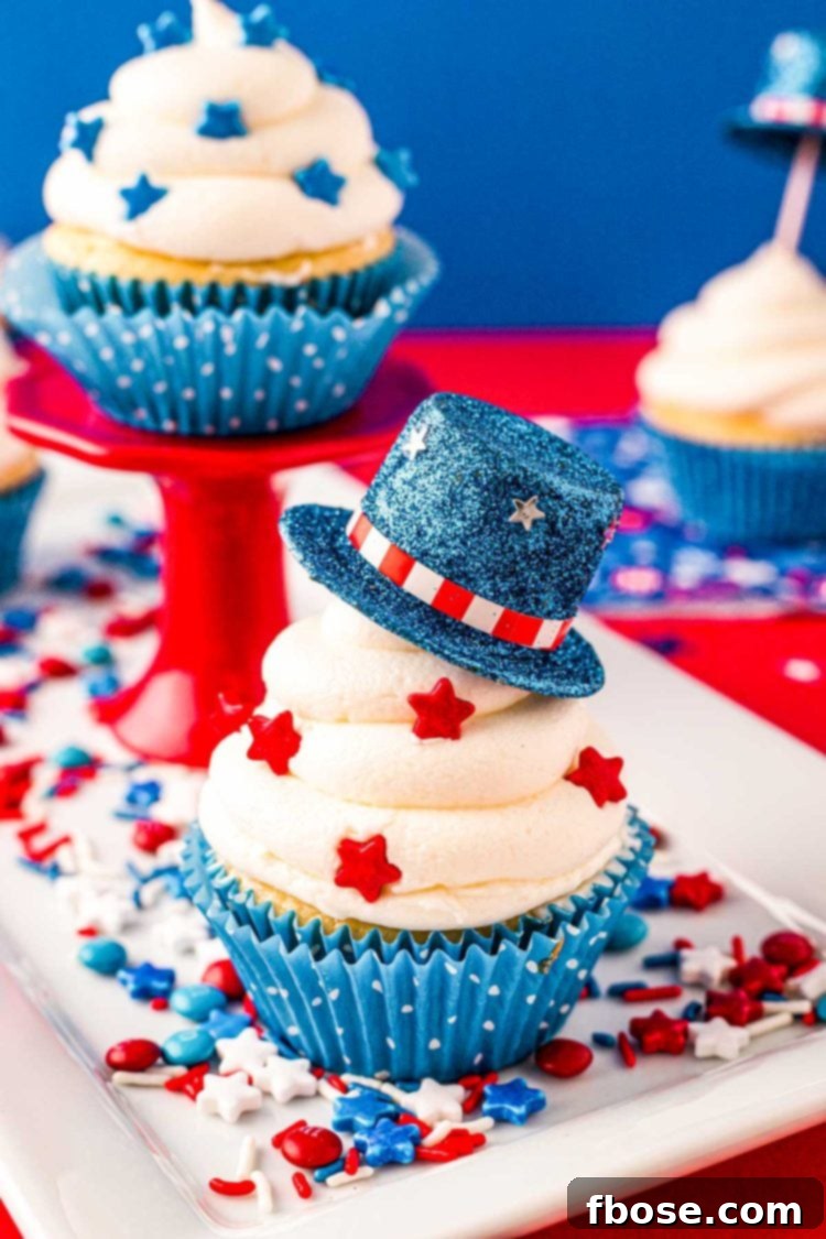 Close up photo of a 4th of July cupcakes decorated with a mini blue top hat and red star sprinkles.