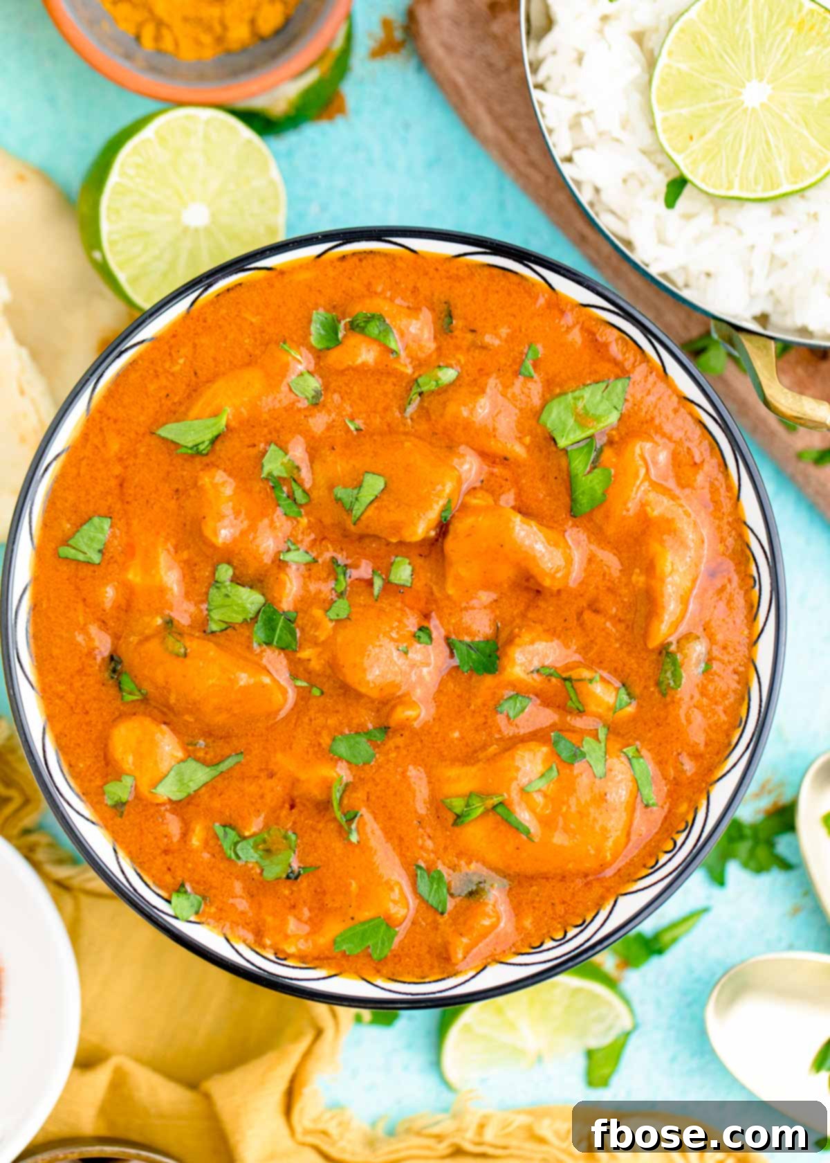 Overhead photo of slow cooker butter chicken in a blue bowl garnished with fresh cilantro, ready to be served.