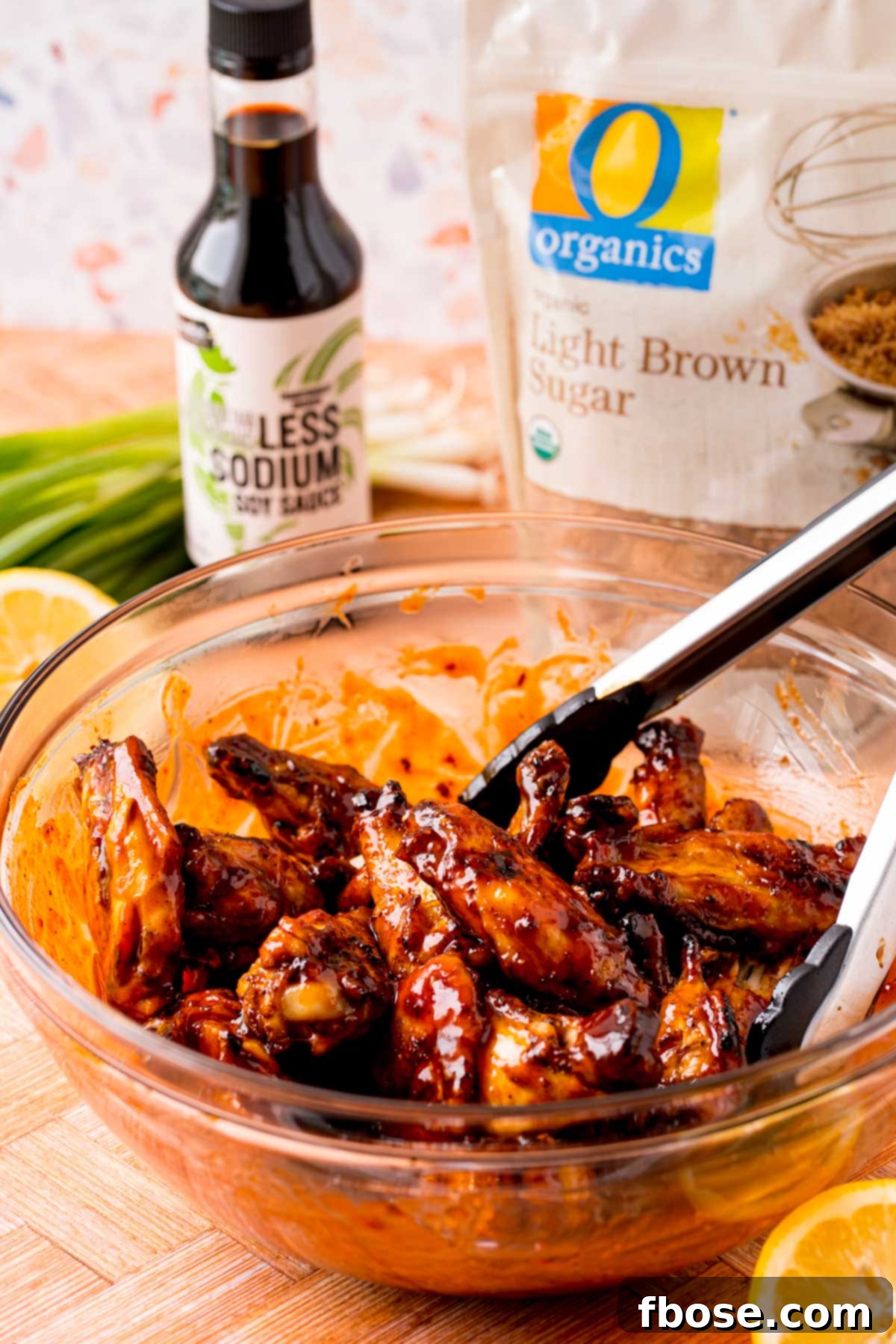 Sticky Korean BBQ Chicken Wings 7 Wings being tossed in Korean BBQ sauce in a glass bowl.