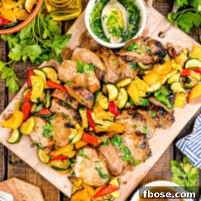 Succulent Grilled Pork Tenderloin 7 Overhead photo of pork tenderloin sliced on a wooden cutting board with vegetables.