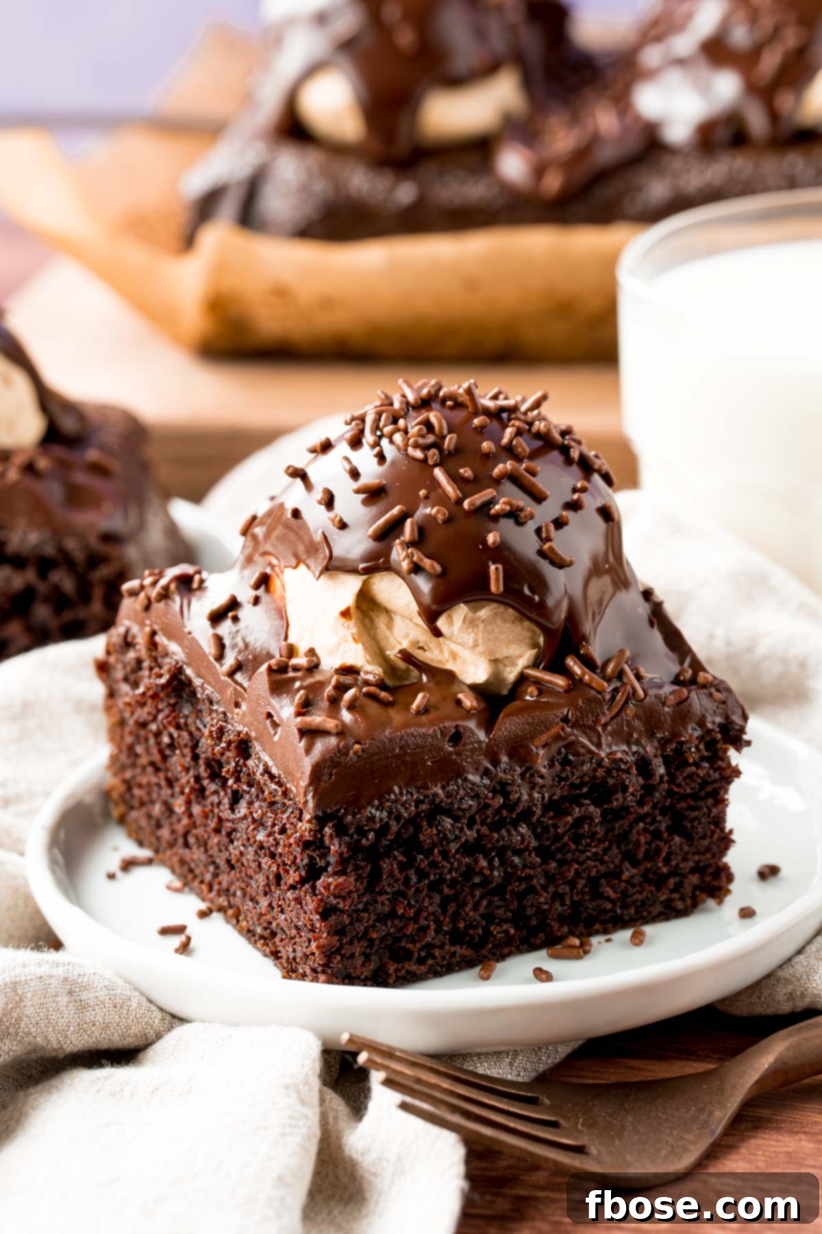 A slice of buckeye cake on a white plate with a glass of milk in the background.