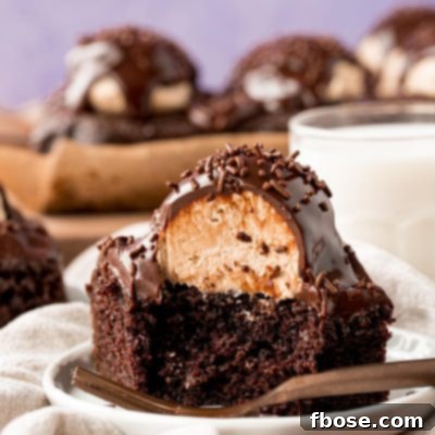 Close up photo of a slice of chocolate cake topped with a scoop of peanut butter frosting and topped with ganache.