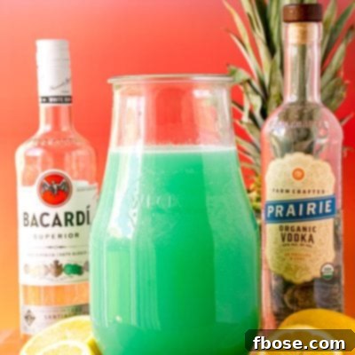 A large pitcher of Tipsy Mermaid Punch on a wooden trivet with a bottle or rum and vodka on each side.