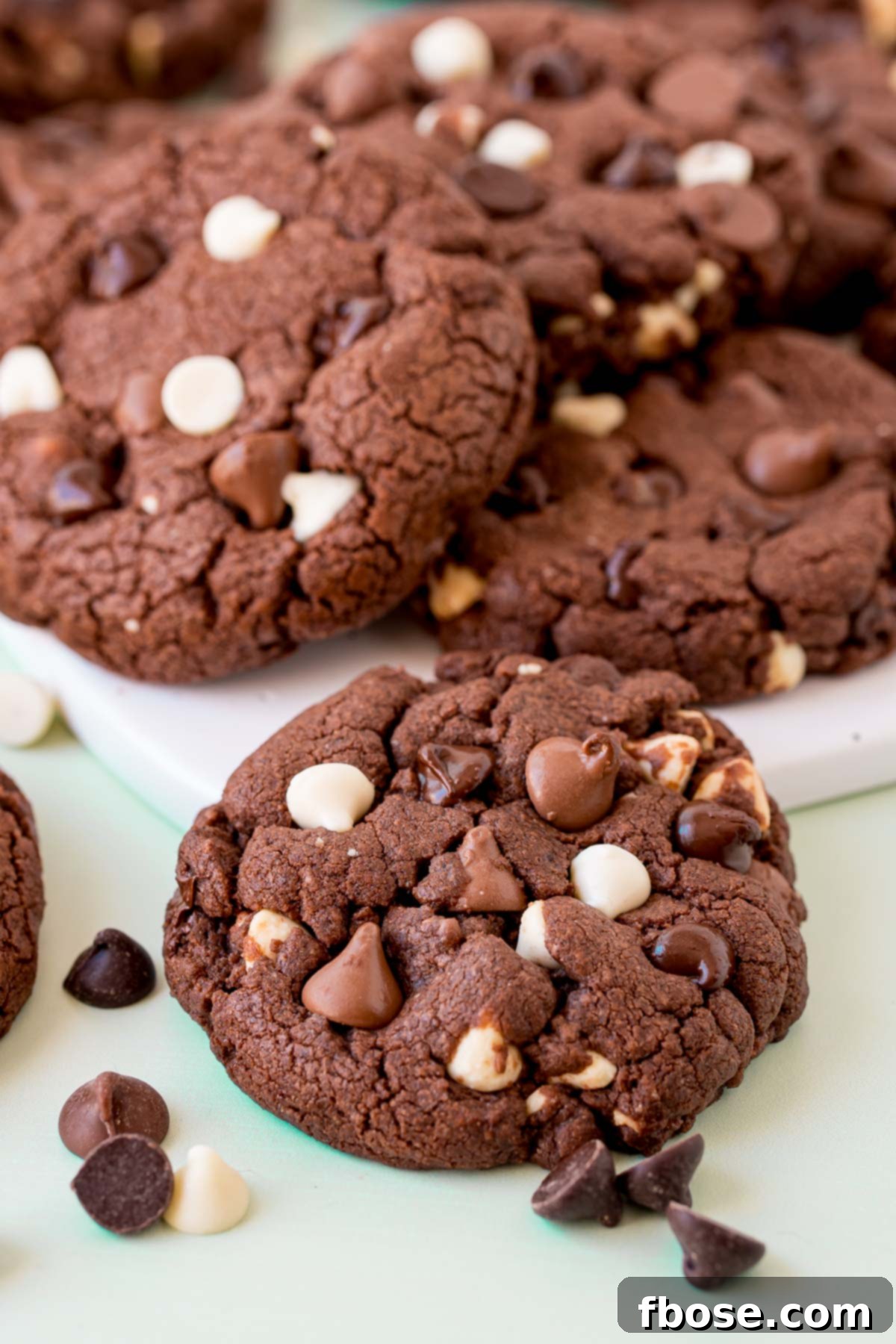 A top-down view of several triple chocolate chip cookies on a white board, showcasing their perfect shape and abundance of chocolate.