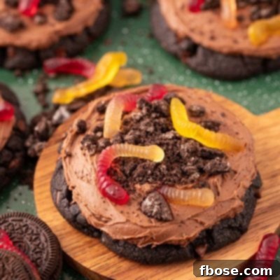 Big dirt cake cookies on a wooden board on a green surface.