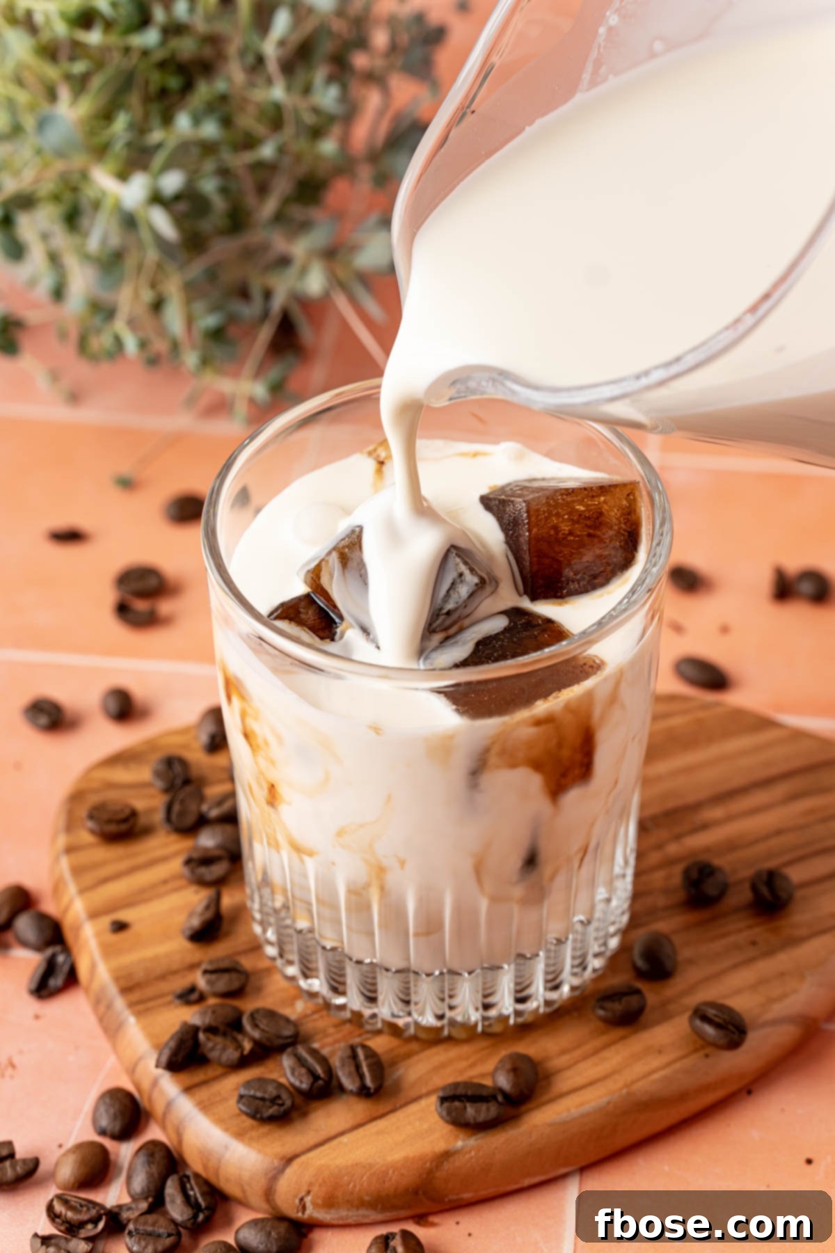 Caffeine Cubes 2 Cream being poured into a glass over coffee ice cubes, creating a delightful swirl of flavors.